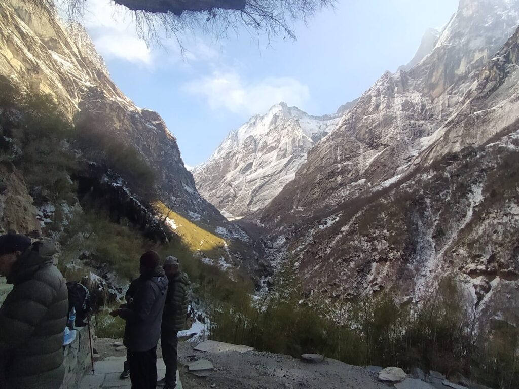 Trekkers on the Annapurna Base Camp trail with snowy mountains ahead.