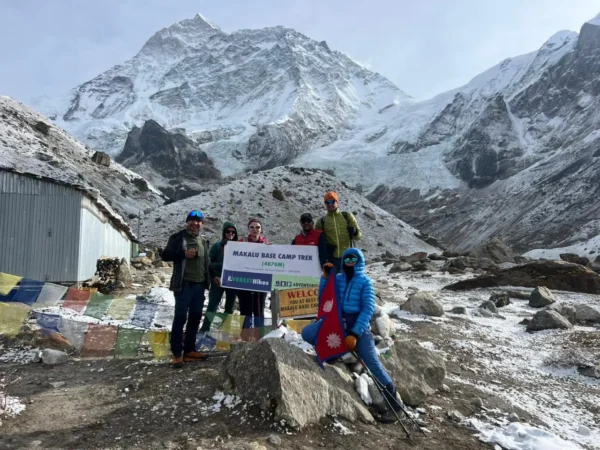 Six trekkers are standing at Makalu Base Camp with a banner of Everest Hikes.