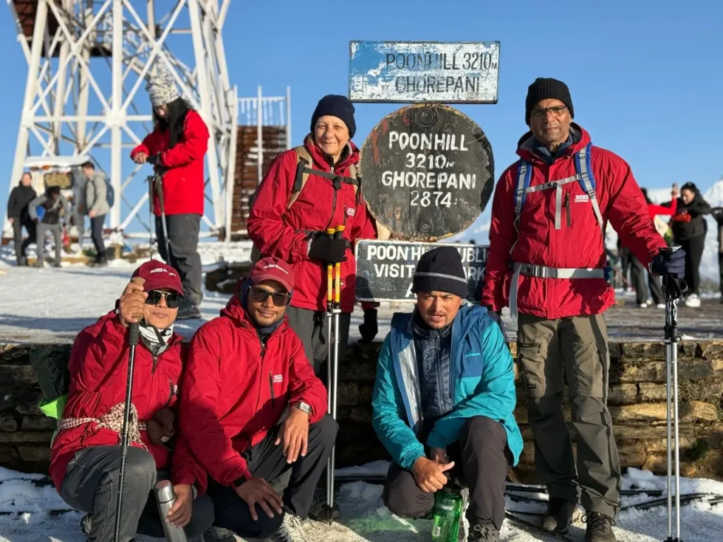 Trekkers posing at the viewpoint of Poon Hill with snow and clear mountain views during sunrise trek