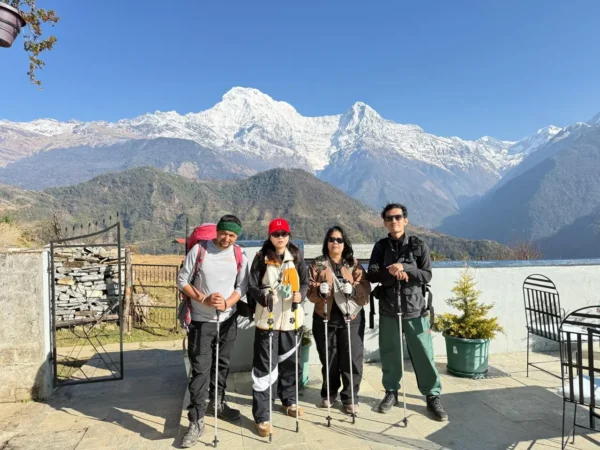 Four trekkers are carrying backpacks and enjoying the beautiful experience of Annapurna South in the sunshine.