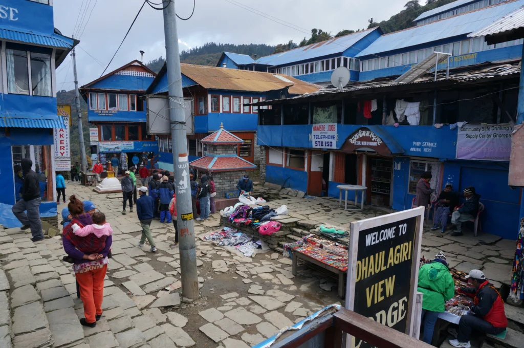Ghorepani village street with lodges, shops, and trekkers along the Annapurna trekking route in Nepal.