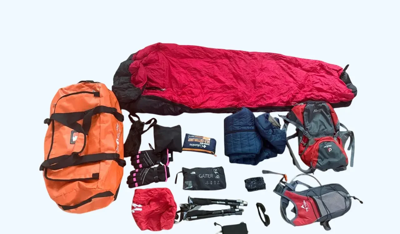 Trekking gear set with backpack, sleeping bag, jacket, gloves, trekking poles, and accessories.