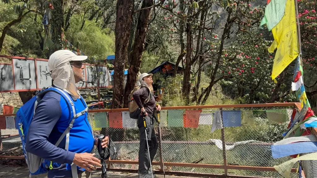 Annapurna Base Camp Trek Cost: Complete 2026 Guide 10 Trekking scene on the way to Annapurna Base Camp with hikers carrying backpacks and prayer flags in Nepal