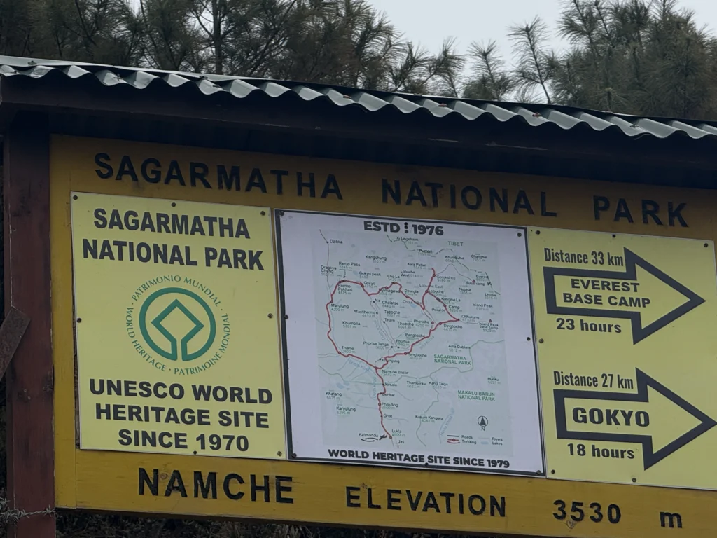 Signboard of Sagarmatha National Park at Namche Bazaar showing directions to Everest Base Camp and Gokyo with elevation details