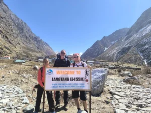 Three trekkers standing near the welcome sign at 3,455 meters during the Langtang Valley Trek in Nepal.